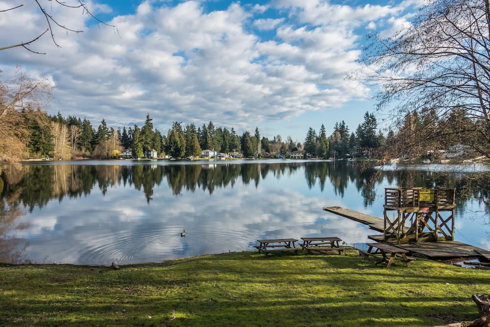 Homes, trees and sky are reflected in the water of Mirror Lake in Federal Way, Washington.